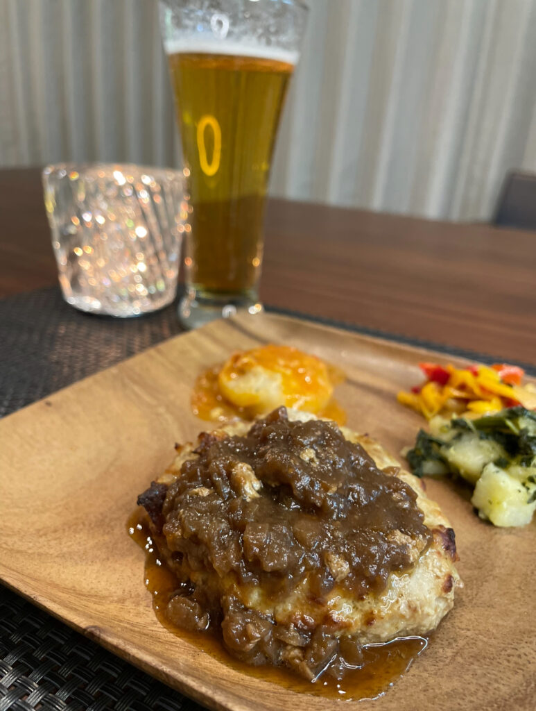 デリピックス人気ナンバーワンのハンバーグをビールと一緒に食べてる写真