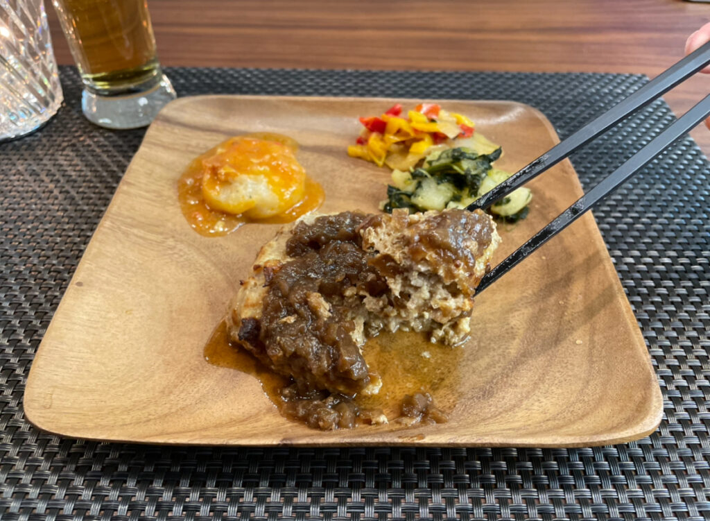 デリピックスのハンバーグをお箸で摘んでいる写真